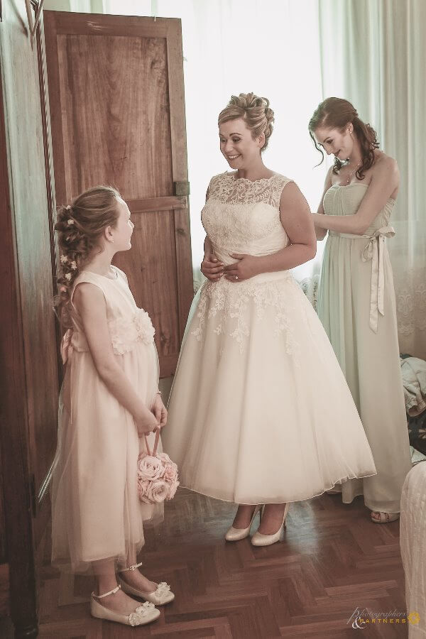 Bridesmaid and baby help help the bride dress up
