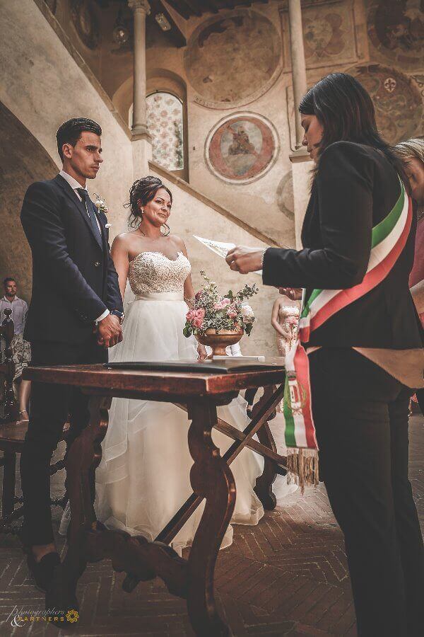 Bride and groom at wedding ceremony listen to registrar speech before exchanging rings