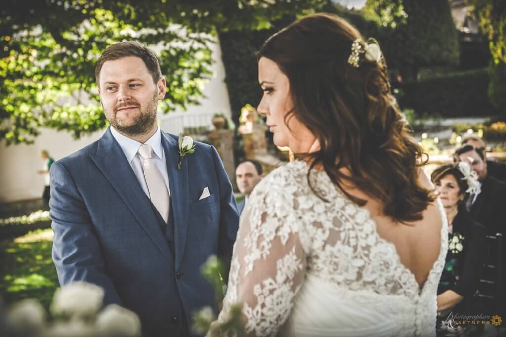 Bride and groom at wedding ceremony listen to registrar speech before exchanging rings